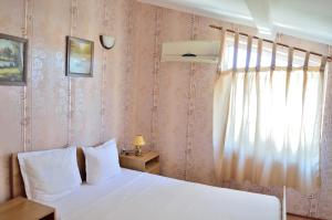1 dormitorio con cama blanca y ventana en Hotel Kibor en Gŭlŭbovo