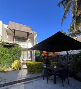 un tavolo e delle sedie nere sotto un ombrellone nero di LA VILLA 1 Deluxe2 Mont Choisy MAURITIUS a Mont Choisy
