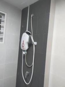 une douche avec un tuyau fixé à un mur dans l'établissement Acacia Residences KLIA by Wanfik Homesta, à Sepang