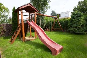 a wooden playground with a slide in a yard at Főnix Apartmanház in Hajdúszoboszló
