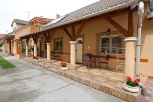 een huis met een overdekte veranda met een tafel en stoelen bij Főnix Apartmanház in Hajdúszoboszló