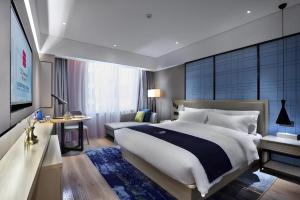 een slaapkamer met een groot bed en een televisie bij Echarm Hotel Nanning Wuming in Wuming