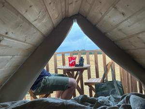 a person sitting on a bed in a tent with a table at Country lodge 