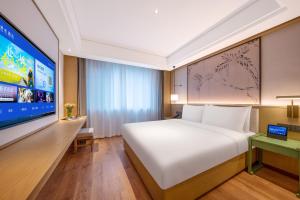 a bedroom with a large bed and a large tv at 武汉汉口金融中心万象城漫心酒店 in Wuhan