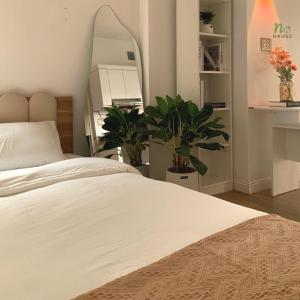 a bedroom with a large white bed and plants at Nạ House - Homestay Đất Cảng in Hai Phong
