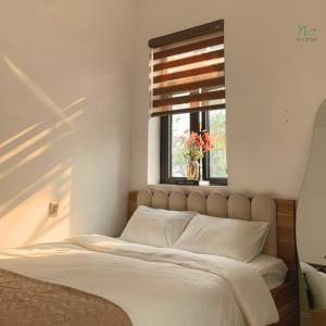 a bedroom with a large bed with a window at Nạ House - Homestay Đất Cảng in Hai Phong