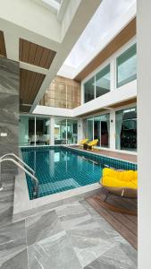 a swimming pool with a yellow couch in a building at De Flourishing Hill Pool Villa , Cha Am in Cha Am