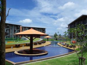 an outdoor pool with an umbrella and tables and chairs at Replay Condo One Bedroom in Bang Rak Beach