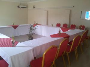 a room with white tables and chairs with red seats at Dich Comfort Hotel - Main Branch in Gulu