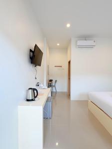 a white hotel room with a bed and a kitchen at Cozy House Chanthaburi in Chanthaburi