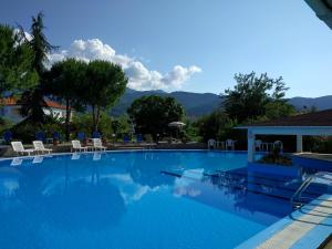 a large blue swimming pool with chairs and mountains in the background at Laios Hotel (Adults Only) in Limenas