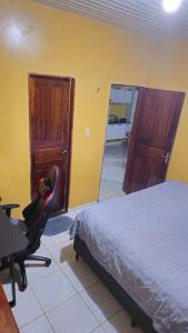 a bedroom with a bed and a desk and a chair at Casa 3 quartos em Juruti in Juruti