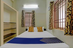 a bedroom with a bed with a blue and white comforter at Super Collection O Velachery Railway Junction Formerly Vijay Guest House in Chennai