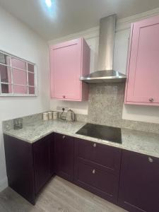 a kitchen with pink cabinets and a sink at Corbridge Apartment in Corbridge