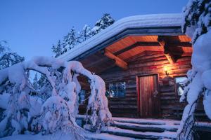 uma cabana de madeira na neve à noite em Kakslauttanen Arctic Resort - Igloos and Chalets em Saariselka