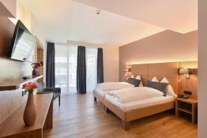 a hotel room with two beds and a tv at Hotel Central in Engelberg