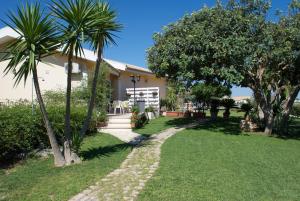 a house with palm trees and a walkway at Le Case di Giulia in Sampieri