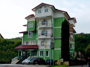 a green building with cars parked in front of it at Hotel Belvedere in Piatra Neamţ