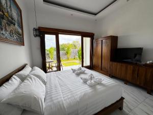 a bedroom with a bed with white sheets and a television at Dé Kamala Bali in Nusa Dua