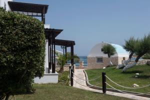 a house with a fence and palm trees and the ocean at Contaratos Beach Hotel in Naousa