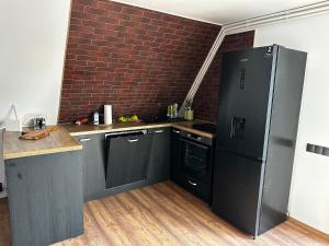 a kitchen with a black refrigerator and a brick wall at Cabană Panoramic Aframe in Dealu Negru +12 photos
