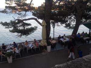 a group of people sitting at tables near the water at Apartment Josip in Korčula
