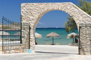 an archway leading to a beach with umbrellas and the ocean at Contaratos Beach Hotel in Naousa