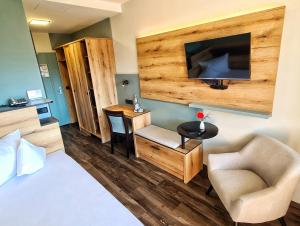 a hotel room with a bed and a chair and a television at AURA-HOTEL Saulgrub in Oberammergau
