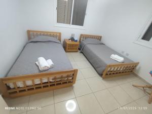 two twin beds in a room with a tiled floor at 3-Bedroom House Near the Beach in Paralimni