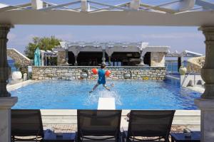 a man is in the water in a swimming pool at Contaratos Beach Hotel in Naousa