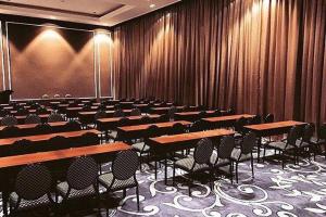 una sala de conferencias con mesas y sillas. en Royal Asnof Hotel Pekanbaru en Pekanbaru