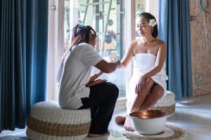 a woman is getting her hair done in front of a window at Summer Bungalow, Ideal for Families, One Room with 2 Beds, Separated Sleeping Corner, Shower, AC, 2 TVs in Lakahembi