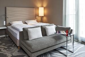 une chambre d'hôtel avec un lit et un canapé dans l'établissement LÉGÈRE HOTEL Bielefeld, à Bielefeld