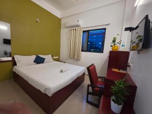 a bedroom with a bed and a chair and a window at Sulthan Hotel & Restaurant in Cochin