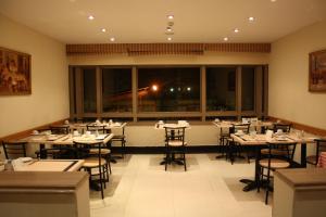 a restaurant with tables and chairs and a large window at Green Plaza Inn in Alexandria