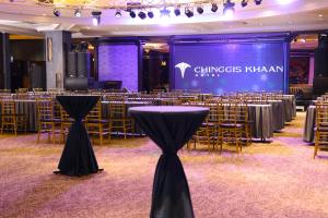 una sala banchetti con tavoli, sedie e un palco di Chinggis Khaan Hotel a Ulaanbaatar