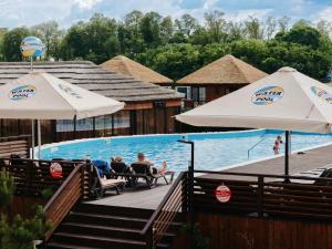 two people sitting in chairs next to a swimming pool with umbrellas at Waterloo Village in Dnipro
