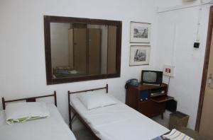 two beds in a room with a mirror and a tv at 10-Z Bunker in Brno