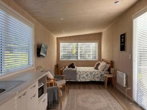 a room with a bed and a kitchen with a bed at Cotman Cottage on Coatesville in Kumeu