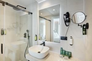 a white bathroom with a sink and a shower at Sercotel Cruz Del Mar in Chipiona
