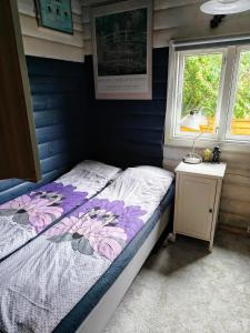 a small bedroom with a bed and a night stand at Charmerende Norsk Bjælkehytte med fibernet in Slagelse