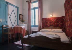 a bedroom with a bed with a red headboard and a table at Pension Nora in Chania