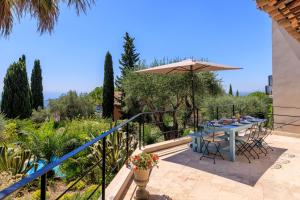 un patio con una mesa y una sombrilla en VILLA les TEMPLIERS, en Vence