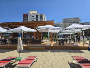 a group of umbrellas and tables and chairs on a beach at Sandy Vibes Apartments in Durrës