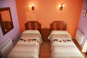 2 Betten in einem Zimmer mit orangefarbenen Wänden in der Unterkunft Casa Rural Gaztelubidea in Bernedo