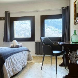a bedroom with a desk and a chair and two windows at Hostal Moliné in Bruguera