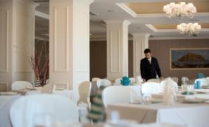 a man standing in a dining room with tables at Hotel Caparena in Taormina