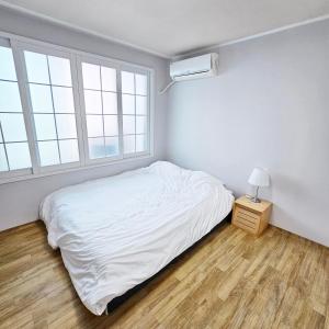 Un dormitorio blanco con una cama y una ventana. en Ocean House PH, en Pohang