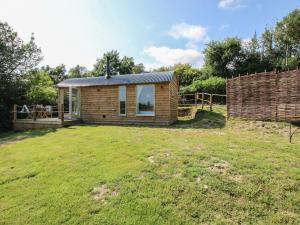 a small wooden cabin in a field with a yard at Swallows Nest in Bucknell