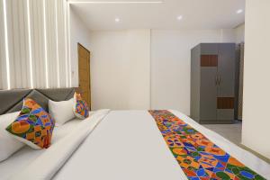 Un dormitorio con una cama grande con almohadas de colores. en FabHotel Ayodhya Palace, en Bangalore